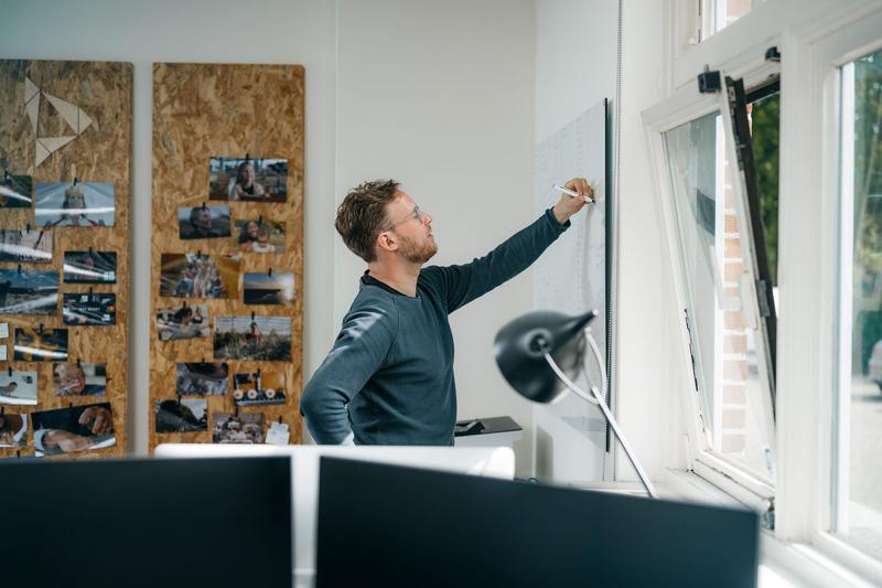 Man schrijft op whiteboard in kantooromgeving Man werkt aan videostrategie door aantekeningen te maken in een kantooromgeving