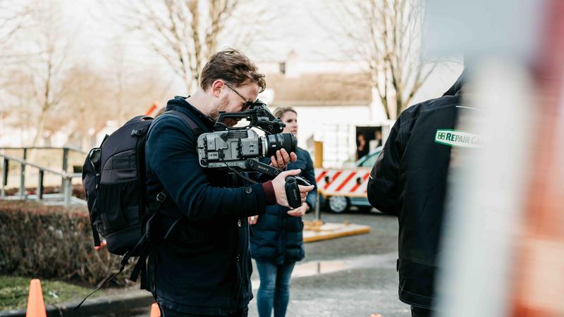 Cameraman met schoudercamera filmt op locatie, straatsetting Cameraman filmt met een schoudercamera tijdens een video-opname op locatie