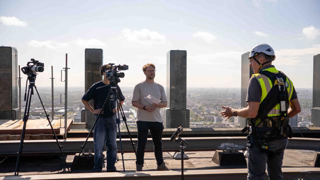 Interview bovenop Jubi toren Twee videomakers van Pro Motion Film interviewen inspecteur op dak van de Jubi Torens in Den Haag